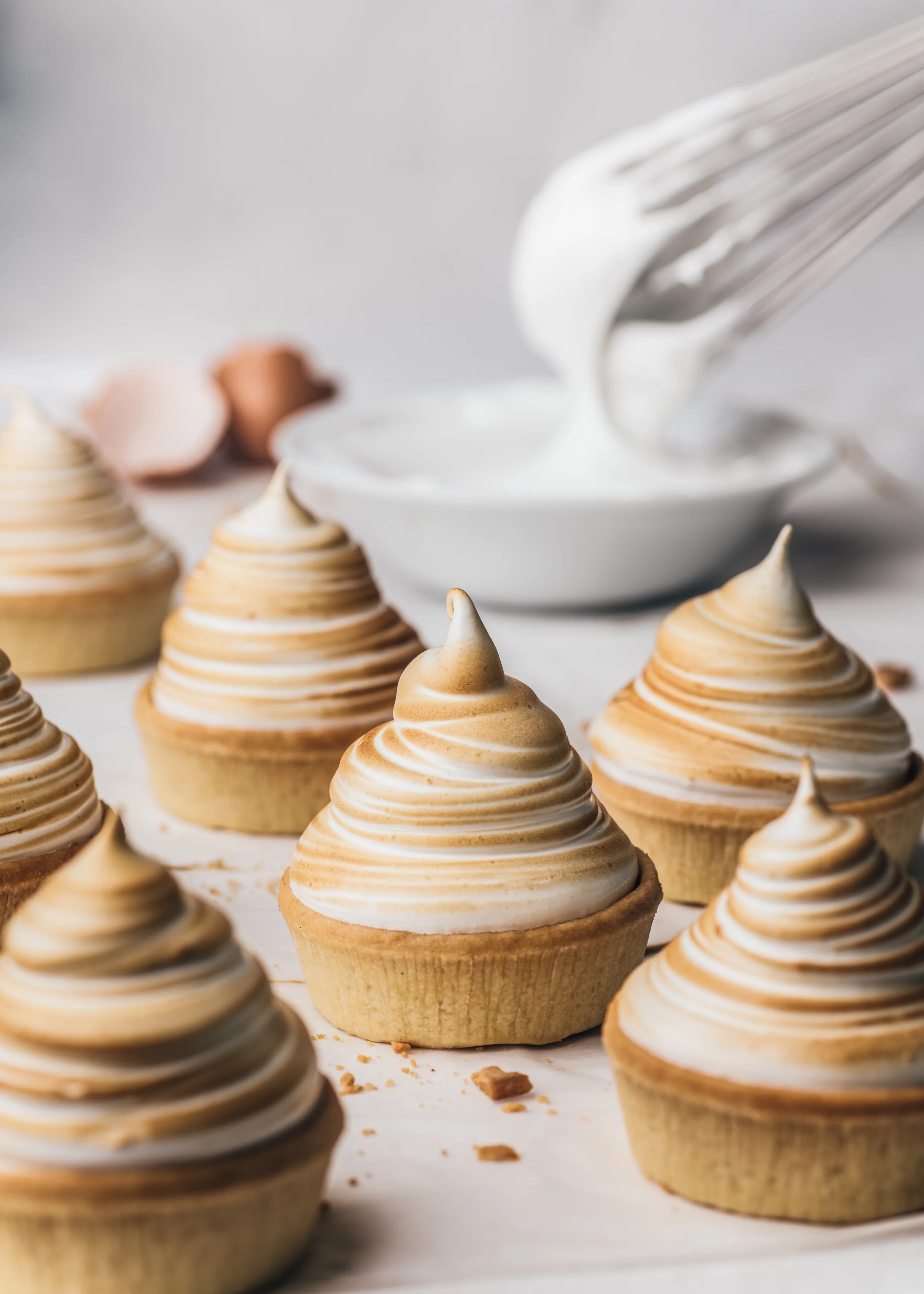 Individual lemon meringue tarts with tall torched meringue peaks.